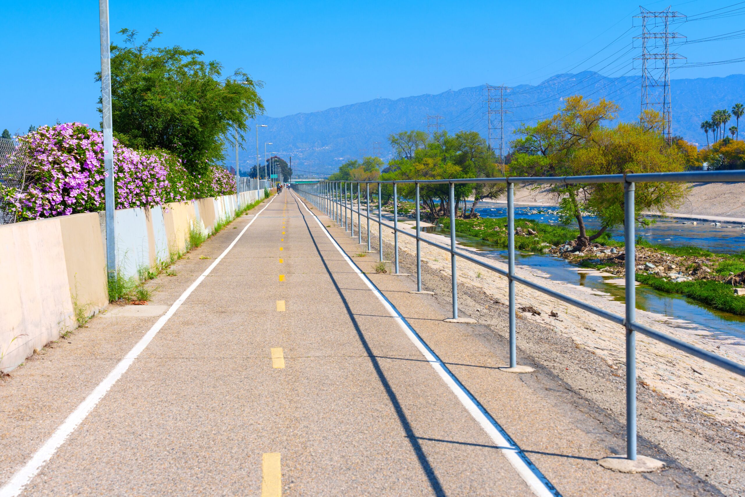 LA River Bike Path through Elysian Valley. A bike route divided by a yellow line. A metal railing alongside with the river below.