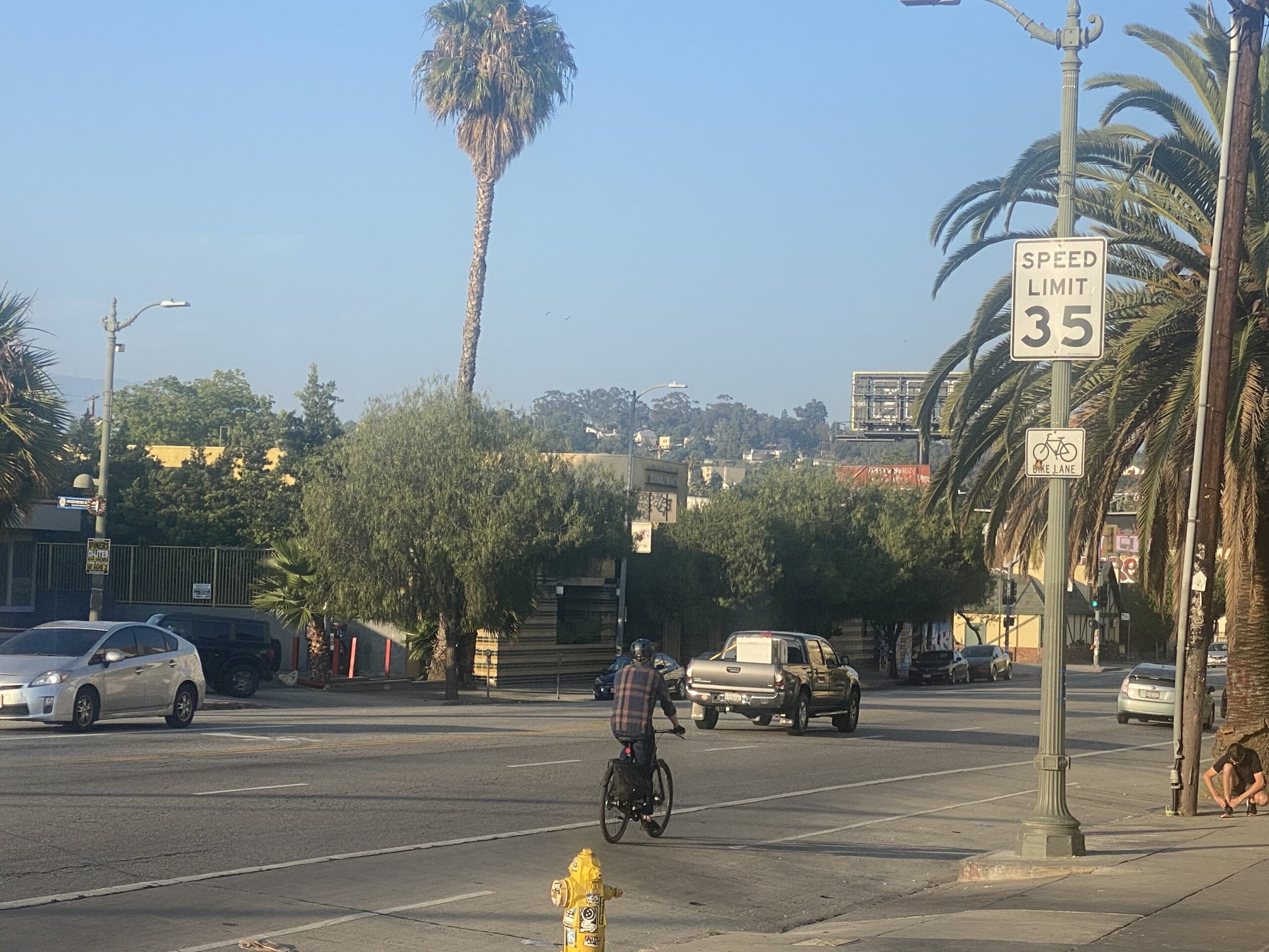 Class II Standard bike lane along Sunset Boulevard near Alavardo St. A cyclist using the lane with "bike lane" street sign above.